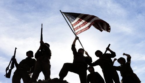 US Army Soldiers on hill with American flag.